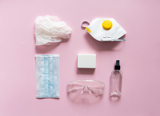 Obraz na płótnie Canvas Medical protective mask, respirator ffp, soap, rubber gloves, antiseptic and protective glasses lie on a pink background. Anti-virus protection kit against covid-19. Coronavirus pandemic 2019.