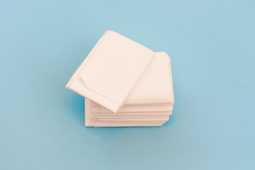 A pack of new hygienic white paper tissues or napkins on light blue background. Tissues for disposable usage.