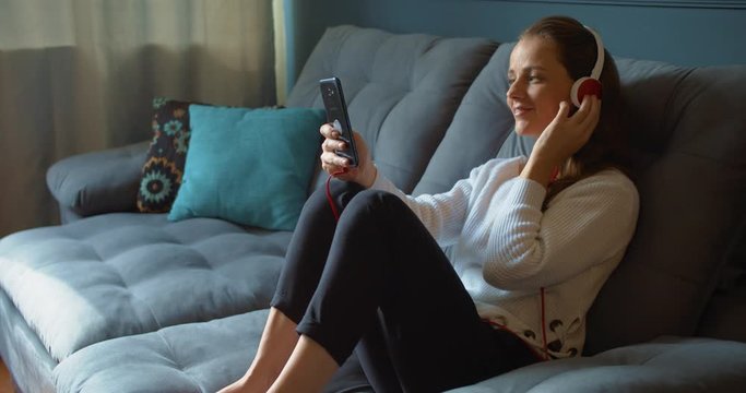 Woman listening music inside her house with headphones