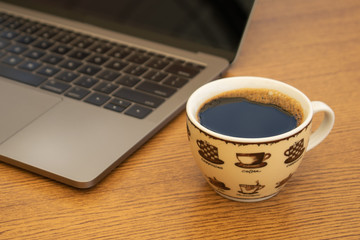 Coffee Cup next to a Computer