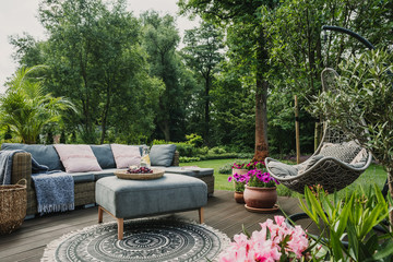 Classy furniture on wooden terrace in green beautiful garden