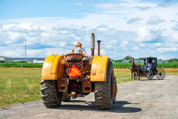 Small Boy Drives Tractor and Amish Buggy