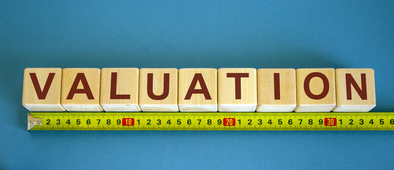 Valuation word on cubes arranged behind the ruler on blue background.