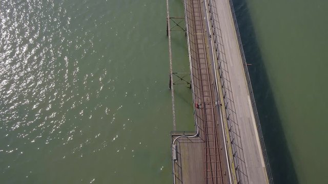 Drone or aerial view of Southend pier stretching out into the sea with tilt to show full length. A beautiful ethereal clip with light cloud and shimmering sea
