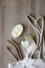 Canvas tote bag with zero waste products: menstrual cup, soap, reusable straws and bamboo toothbrush. Top view.