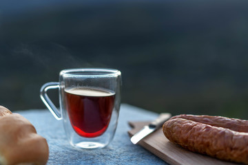 Sausage, baguette and a glass of tea on a rustic background.
