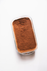 Tiramisu cake  on a baking dish, top view on a white background