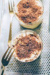 Tiramisu served on small  glasses, with golden fork