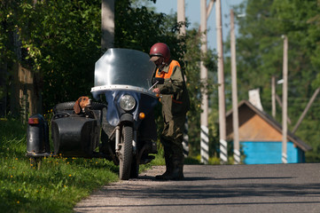 

Ostrovets, Grodno region, Republic of Belarus - July 27, 2016: grandfather rides an retro motorcycle with his dog. Illustrative editorial.
