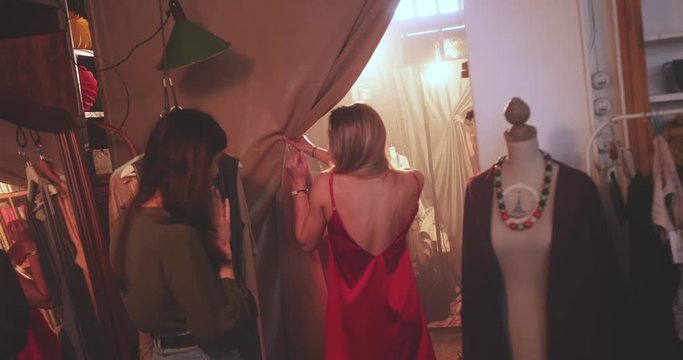 Blonde woman showing dress to friend in boutique store