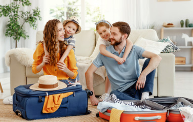 Cheerful family with suitcases on floor looking at camera.