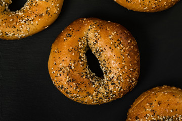 Freshly Baked Bagels Topped with Sesame Seeds, Poppyseeds, Garlic and Onion on Black Background. Selective focus.