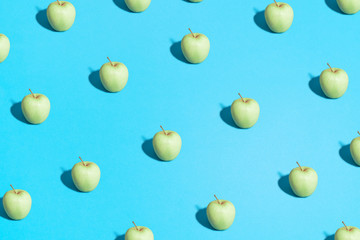 Minimal flat lay food texture. Summer abstract trendy fresh concept. green Apple pattern on bright light blue background, copy space.