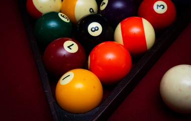 Close up of billiard balls racked in a triangle on a red felt pool table