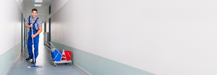 Happy Male Worker With Broom Cleaning Office Corridor © Andrey Popov