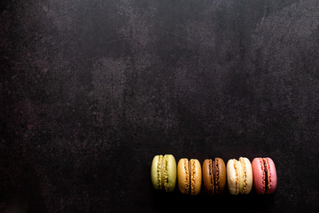 Macarons colorés disposés en ligne sur fond noir