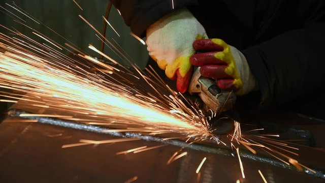 worker grinding weld seam with grinder machine and sparks. 4k