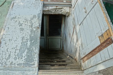 Fototapeta na wymiar descent to the basement on the street with stone steps and an open shabby old wooden door