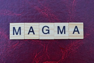 text of word magma from gray wooden small letters with black font on an red table