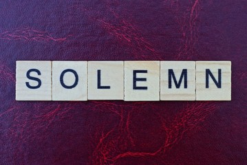  word solemn from gray wooden small letters with black font on an red background