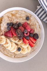 Healthy breakfast brunch oatmeal. Healthy lifestyle. Fruits and berries. Strawberry, raspberry, blackberry, blueberry, banana. Maple syrup drizzle. Cinnamon topping. White plate. Weekday breakfast