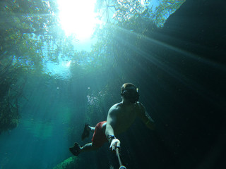 Fototapeta na wymiar Man takes selfie while freediving in Casa Cenote in Tulum, Quintana Roo, Mexico