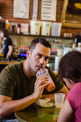 Guy is drinking a pink healthy smoothie in a coffee shop in Riverside, California, USA