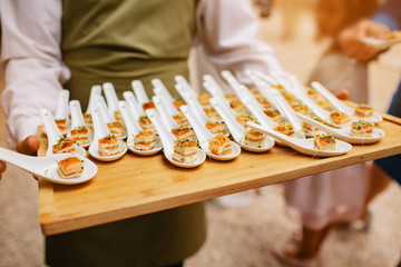bartender with table of salmon canapes on a teaspoon during the cocktail of an outdoor event