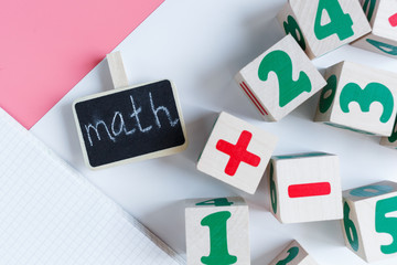 Colorful wooden math cubes with numbers, notebook on pink white background. Interesting, fun mathematics for kids. Education, back to school concept	