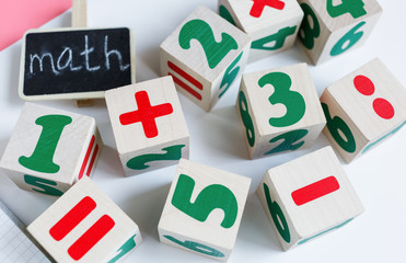 Colorful wooden math cubes with numbers, notebook on pink white background. Interesting, fun mathematics for kids. Education, back to school concept	