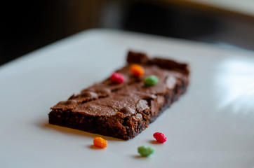 Homemade brownie on white plate. Brownie on black counter. Brownie with decoration. Brownie with...