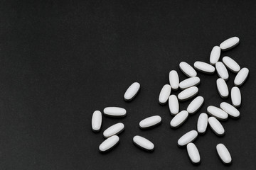 Fototapeta na wymiar white pills on a black background