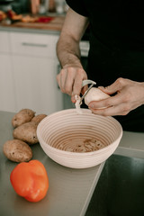 Food preparation. Peeling potatoes. Potato skin. Kitchen counter. Kitchen sink. Making dinner. Man cooks dinner. Husband helps to cook dinner. Peeler utensil. Lifestyle kitchen. Food waste. Vegetable