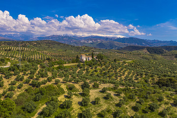 Aerial drone shot of a beautiful green landscape in Spain with a beautiful house with mountains in the background