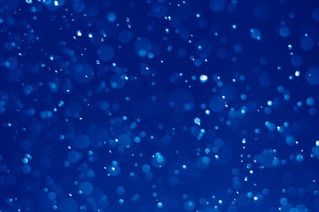 Blue glitter vintage lights background. Blue bokeh on black background.