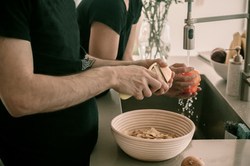 Family cooks dinner together. Dinner preparation. Cooking together fun and happy. Cutting vegetables, peel potatoes. Lifestyle kitchen. White kitchen. Having fun on making dinner.Wife and husband cook