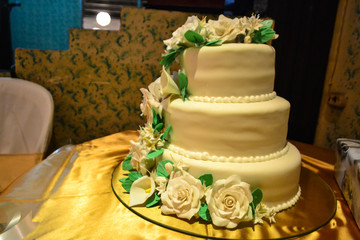 Beautiful white cake decorated with white flowers at a wedding.