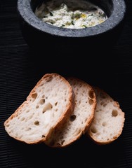 Tzaziki (greek sauce) in a black bowl with some bread at the side.