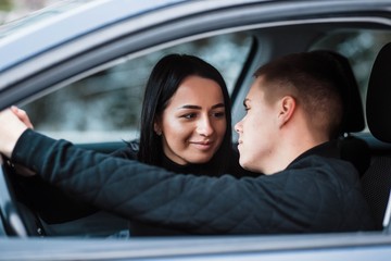 Beautiful couple talking and smiling while sitting in their car. A happy young couple is sitting. Travel and adventure concept. Traveling in comfort. Love in the car.