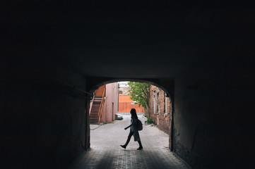 Silhouette of a young girl in an old arch. The concept of walking, loneliness, tourism, slums and poverty.