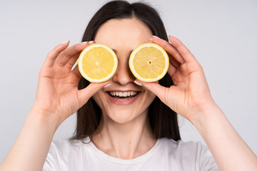 The girl with dark hair in white t-shirt put the eyes of two lemons, smiles, the concept of beauty and health