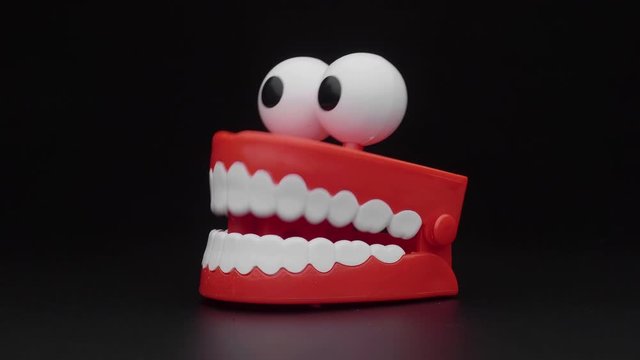 Сhattering teeth toy moving on black background.