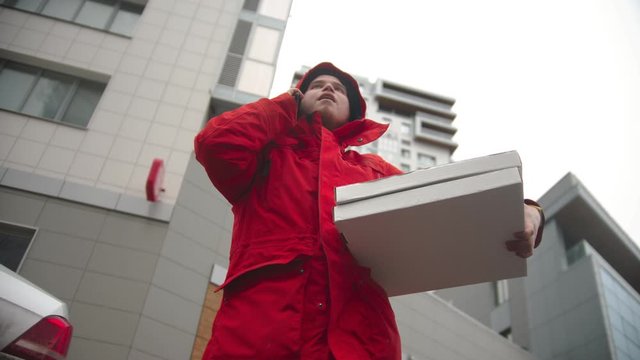 A man courier delivering pizza - talking with customer on the phone