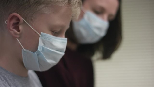 A close up video of a tutor and a pupil both wearing medical protective masks and having a music lesson the camera is then changing to a child's hands pressing the piano keys