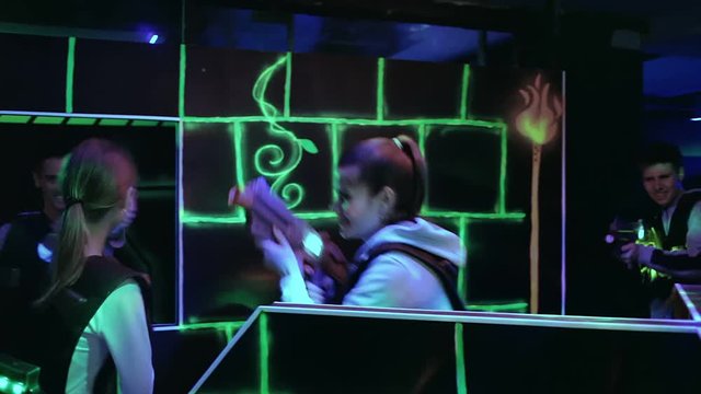 Modern young people with laser pistols playing laser tag on dark labyrinth