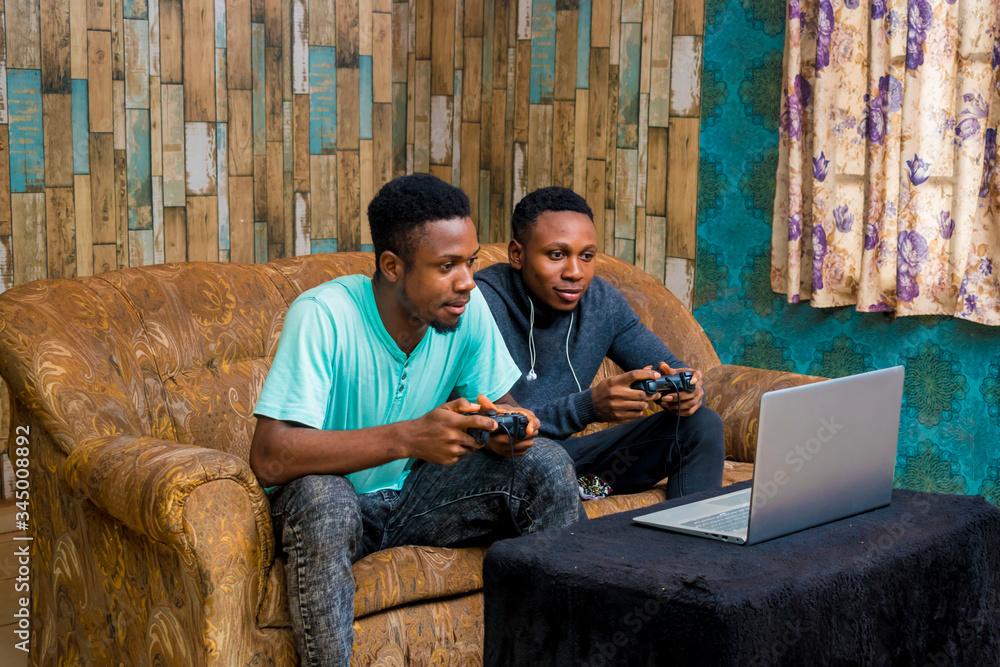 Wall mural young black men playing a video game on a laptop at home