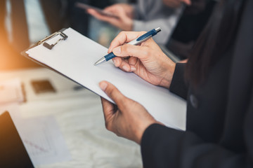 Business Woman is Tanking Note Data While Conference Management Team in Meeting Room, Close-Up of Businesswoman is Writing Agenda Report During Meeting Execution in Office Workplace. Business Teamwork