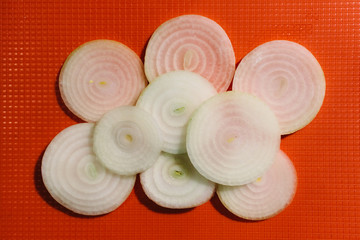 Onion slices on orange chopping board