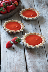 Homemade tartlets with berry cream and fresh strawberry on wooden table