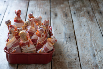 chicken legs wrapped in bacon with sauces close-up in a ceramic dish on the table. horizontal